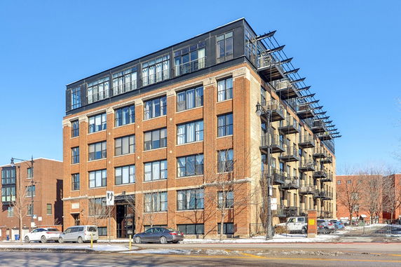 Front view of a multi-story brick building with numerous windows and balconies.