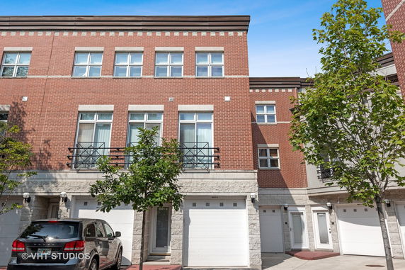 Front view of a multi-story brick townhome with garage.