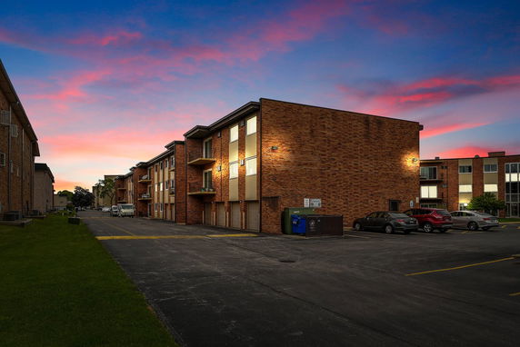 Front view of a multi-story brick apartment building at sunset.