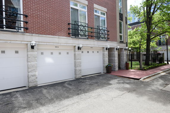 Front view of a multi-story building with three garages and brick exterior.