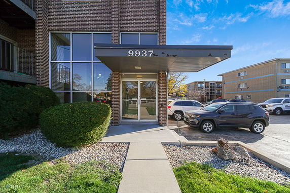 Front view of a brick building entrance with glass doors and windows.