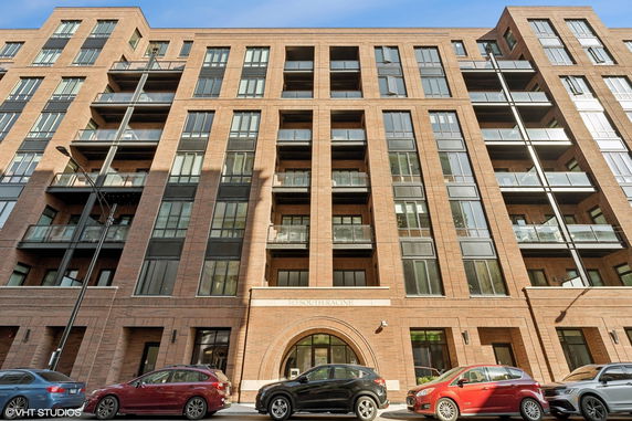 Front view of a multi-story brick apartment building with balconies.