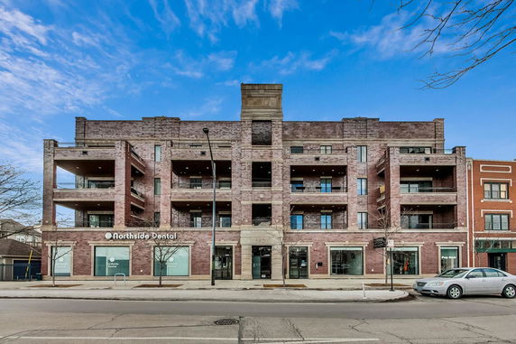 Front view of a multi-story brick building with balconies and commercial space.