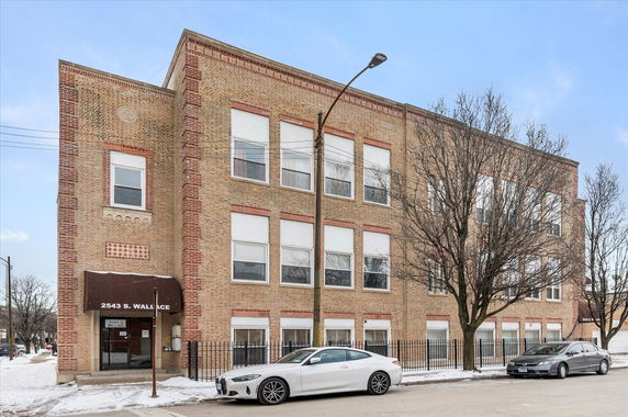 Front view of a multi-story brick building with large windows and an entrance awning.
