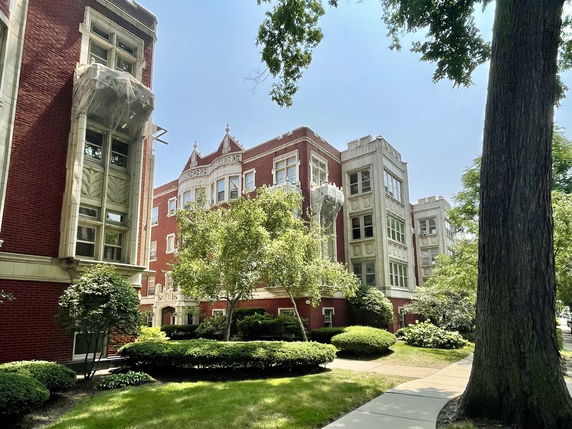 Front view of a brick apartment building with ornate architectural details.
