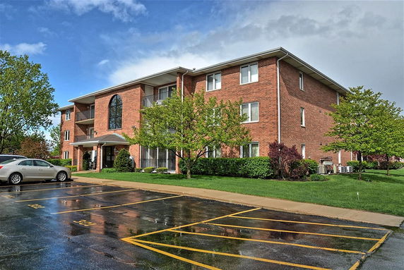 Front view of a three-story brick apartment building with a large arched window.