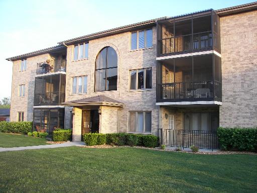 Front view of a three-story building with screened balconies and a brick facade.