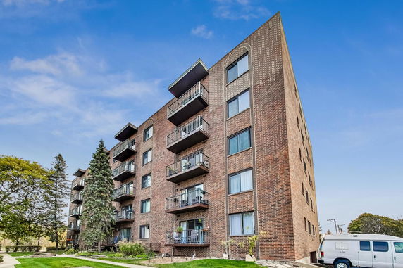 Front view of a multi-story brick apartment building with balconies.