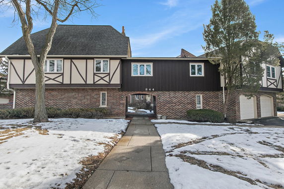 Front view of a two-story house with brick and timber facade and a central walkway.