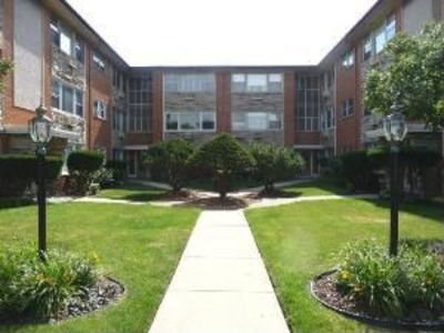 Front view of a multi-story apartment building with a pathway and landscaped garden.