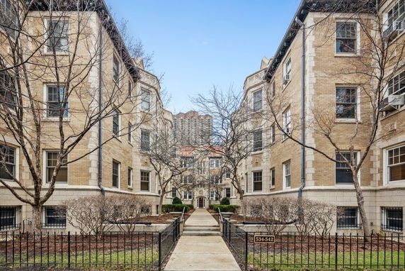 Front view of a multi-story residential building complex with a central walkway.