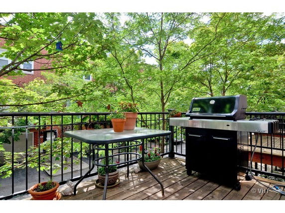 Rooftop area with a grill and table surrounded by trees.