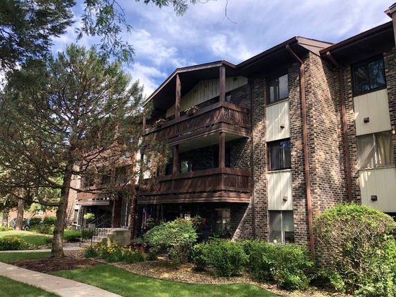 Front view of a multi-story brick apartment building with balconies.