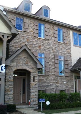 Front view of a three-story house with stone facade and dormer windows.