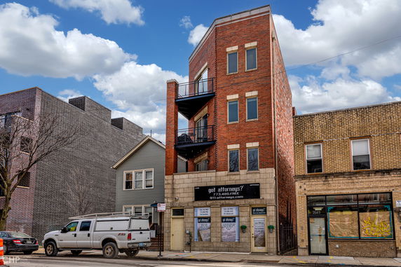 Front view of a three-story brick building with balconies.