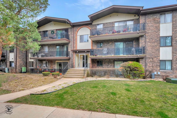 Front view of a three-story apartment building with balconies.