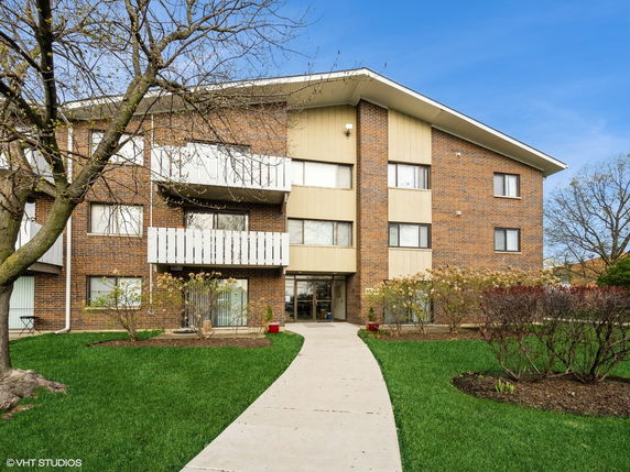 Front view of a multi-story apartment building with a brick facade and balconies.
