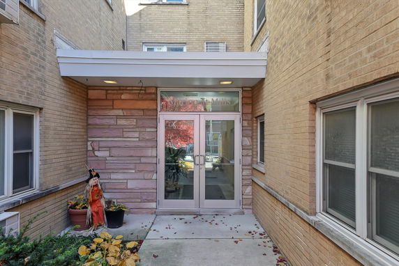 Front view of a building entrance with double glass doors and brick exterior.