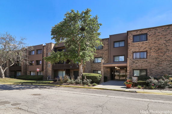 Front view of a multi-story brick apartment building with balconies.
