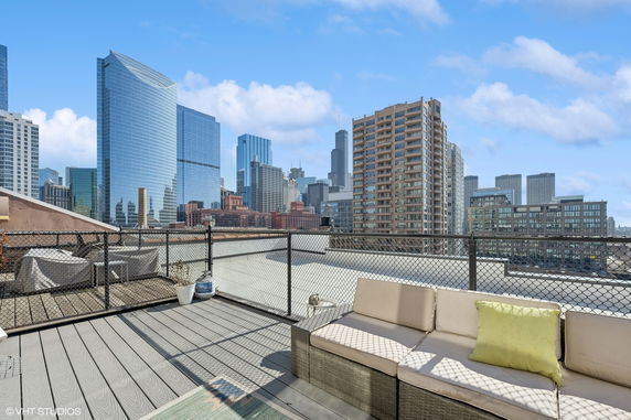 Rooftop patio with seating area and view of city skyscrapers.