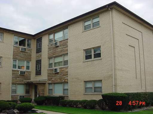 Front view of a three-story apartment building with brick exterior and multiple windows.