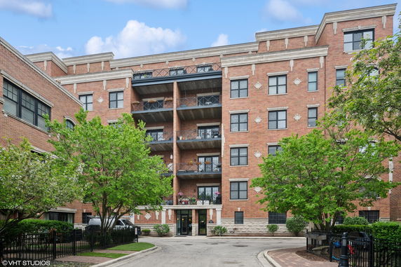 Front view of a multi-story brick apartment building with balconies.