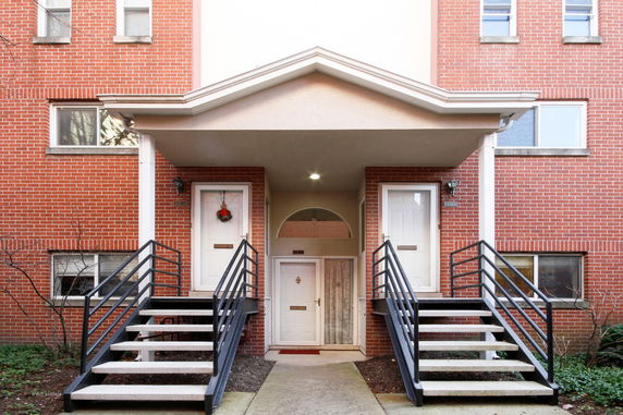 Front view of a brick apartment building with two staircases leading to separate entrances.