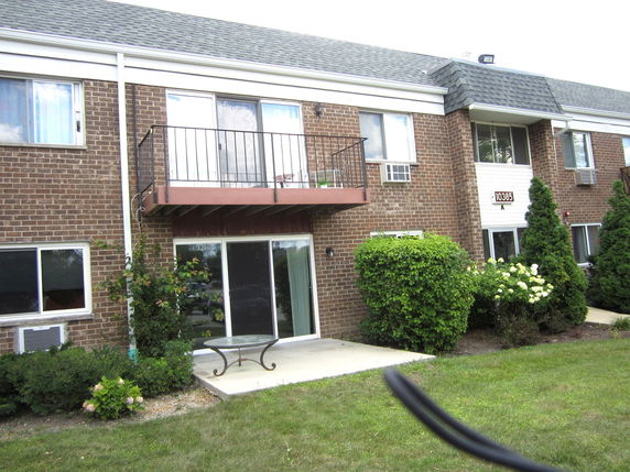 Front view of a two-story brick building with balconies and various windows.