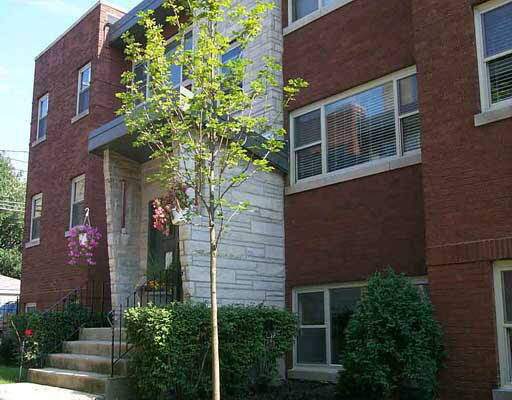 Front view of a brick apartment building with steps leading to the entrance.