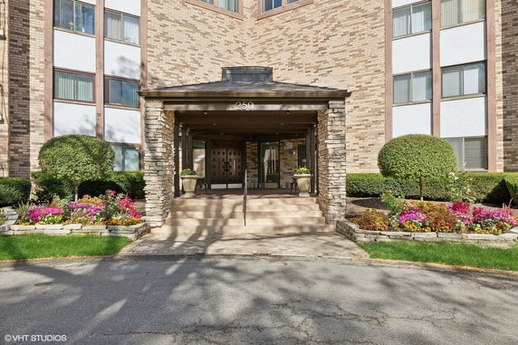 Front view of a multi-story building with a covered entrance and stone pillars.