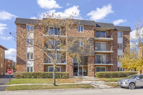Front view of a multi-story residential building with a brick facade and balconies.