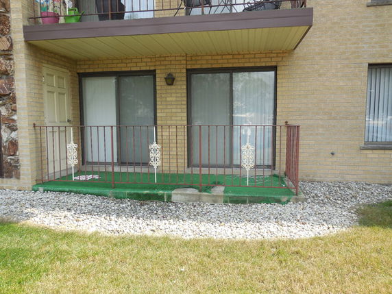 Front view of a building with a small patio and sliding glass doors.