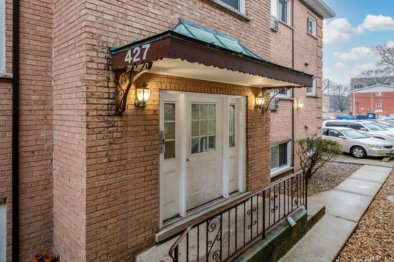 Front view of a brick building entrance with a canopy and two doors.