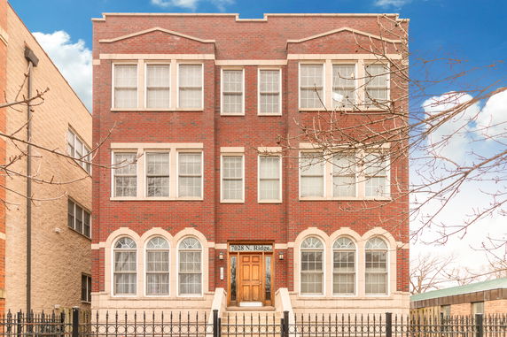 Front view of a three-story brick building with multiple windows and an entrance door.