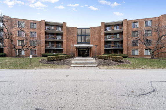 Front view of a multi-story apartment building with brick exterior and balconies.