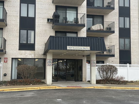 Front view of a multi-story building with balconies and entrance canopy.