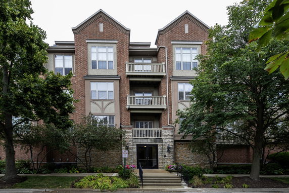 Front view of a multi-story brick apartment building with balconies and large windows.