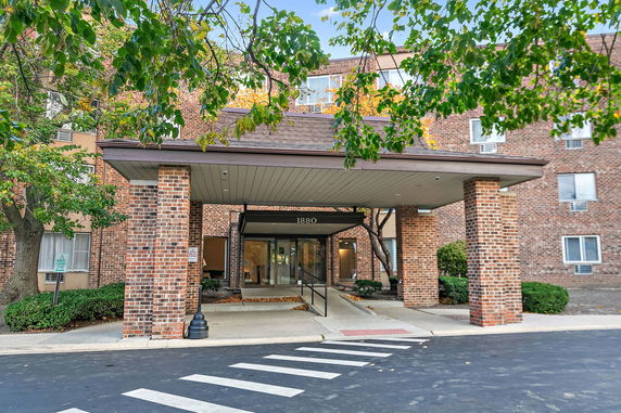 Front view of a multi-story brick building entrance with a covered walkway.