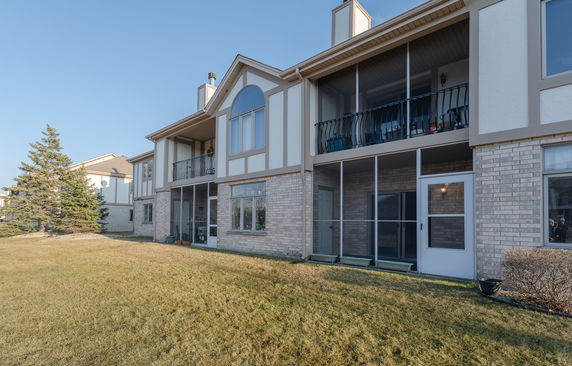 Front view of a two-story residential building with balconies and screened porches.