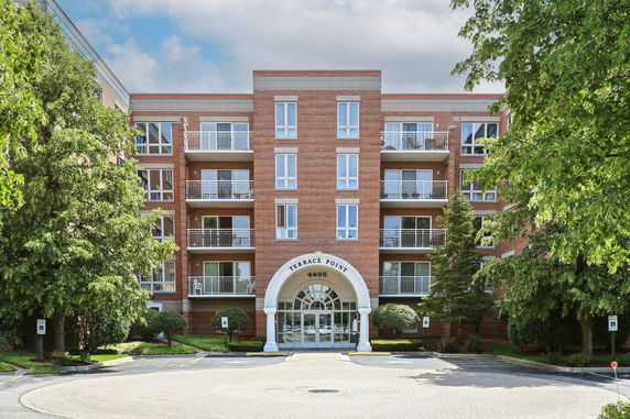 Front view of a multi-story residential building with balconies and a central entrance.