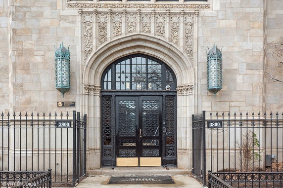 Front view of a building entrance with decorative ironwork and stone carvings.