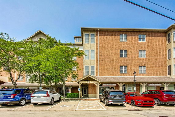 Front view of a multi-story brick building with parking spaces in front.