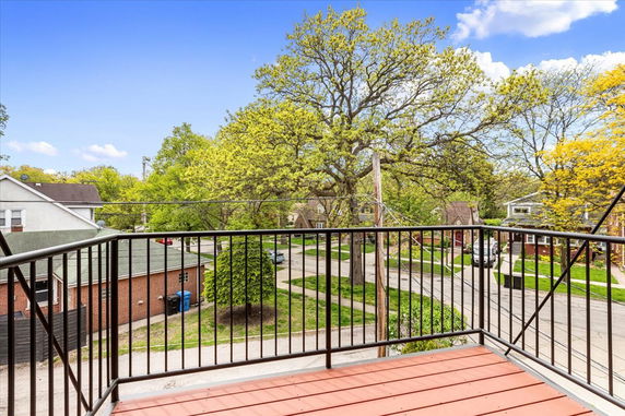 Balcony view of tree-lined suburban street with houses.