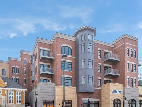 Front view of a multi-story building with a modern design, featuring balconies and large windows.