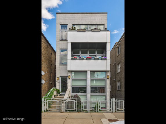 Front view of a three-story modern building with large windows and flower boxes.