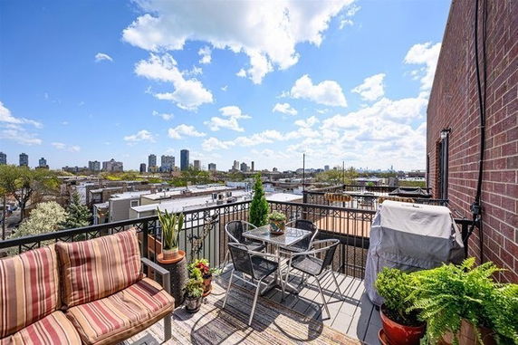 Outdoor rooftop terrace with seating and a view of the cityscape in the background.