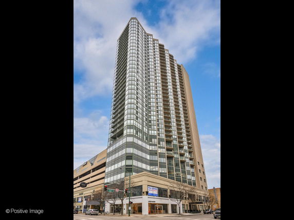 Angled view of a tall glass and concrete high-rise building with balconies.