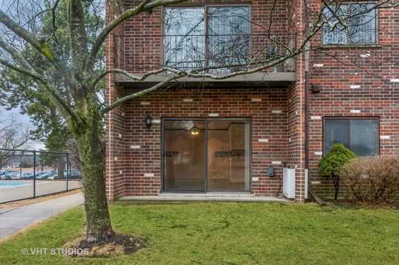 Front view of a brick building with balcony and sliding glass doors.