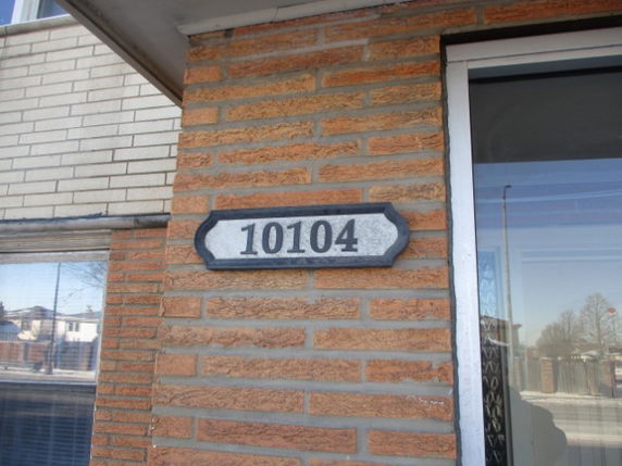 Front view of a brick house with the house number 10104 displayed.