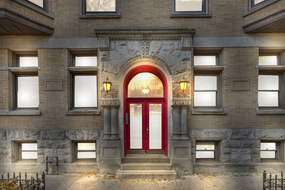 Front view of a building entrance with a red door and decorative stonework.